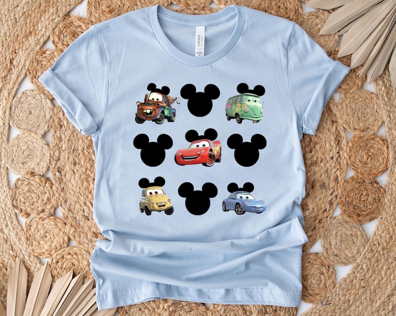 Pu&ograve; includere: Maglietta blu chiaro con una stampa grafica di orecchie di Topolino e personaggi di Cars. I personaggi includono Saetta McQueen, Mate e Mate il carro attrezzi.