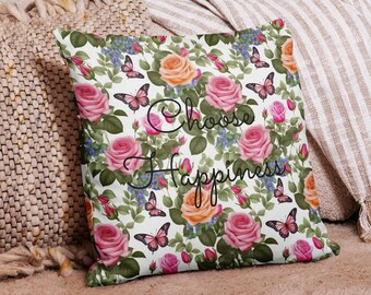May include: White cushion with a floral pattern of pink, orange, and white roses, green leaves, and butterflies. The text "Choose Happiness" is printed in black cursive font.
