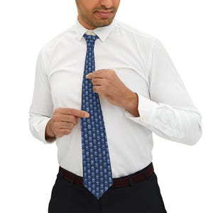 Puede incluir: Una corbata azul con un patrón repetido de cajas de policía azules. La corbata está hecha de un material sedoso y tiene un diseño clásico.