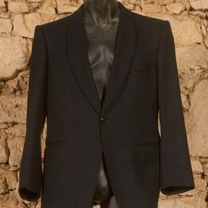 May include: A dark blue blazer with a subtle pattern. The blazer has a single button closure and a notched lapel.