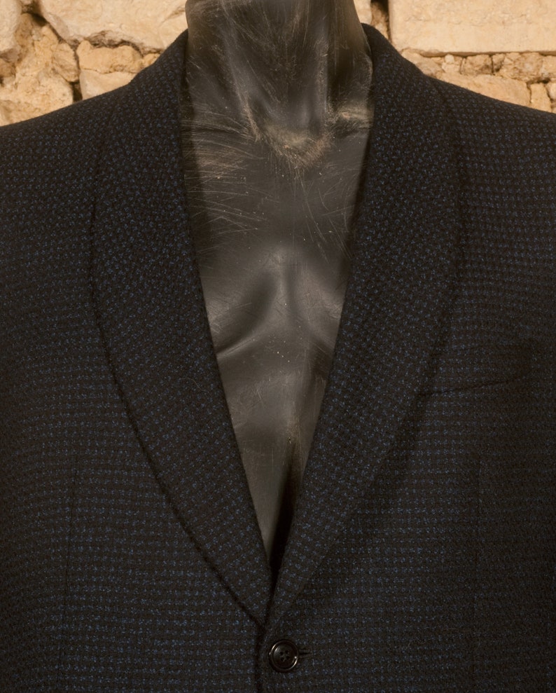 May include: A dark blue blazer with a textured pattern. The blazer has a notched lapel and a single button closure.