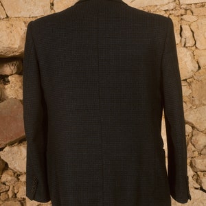 May include: A dark blue blazer with a subtle checkered pattern. The blazer has a single-breasted closure and long sleeves.