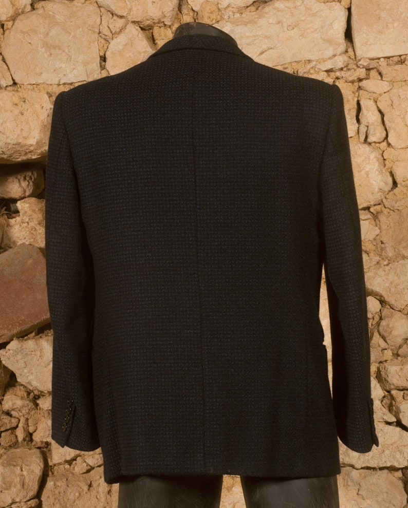 May include: A dark blue blazer with a subtle checkered pattern. The blazer has a single-breasted closure and long sleeves.