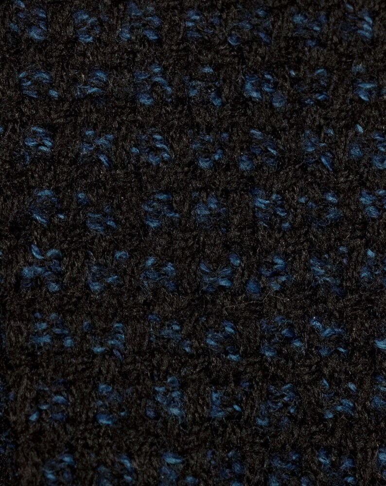 May include: Close-up of a black fabric with a blue flecked pattern. The fabric has a soft, fuzzy texture.