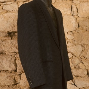 May include: A dark blue blazer with a textured pattern. The blazer has a single button closure and a single pocket on the left side.