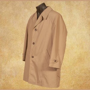 Può includere: Un trench coat beige esposto su un manichino. Il cappotto ha un design classico con chiusura a bottoni, revers a lancia e uno spacco singolo sul retro. Ha due tasche anteriori e polsini abbottonati.