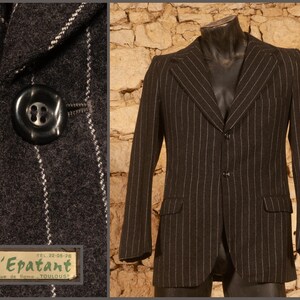 May include: A black and white striped blazer with a single button closure. The blazer has a classic style and is made of a wool blend fabric.