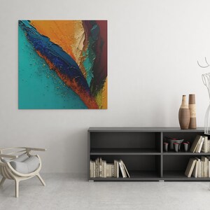 May include: Abstract painting with a teal, blue, gold, and orange color scheme. The painting is hanging on a white wall above a dark gray bookshelf with books and decorative items.