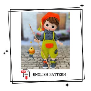 May include: A crocheted doll of a boy dressed in a blue shirt and green overalls with orange accents. He wears an orange hat and holds a fishing rod with a crocheted fish. The text "ENGLISH PATTERN" is visible.