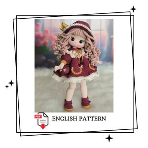 Könnte beinhalten: Eine handgefertigte Häkelpuppe mit einem bordeauxfarbenen Kleid, passendem Hut und kleiner Handtasche. Die Puppe hat lockiges rosa Haar und trägt bordeauxfarbene Stiefel. Der Text "ENGLISH PATTERN" wird darunter angezeigt.