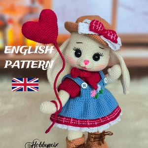 May include: A crocheted bunny doll wearing a blue dress, red shirt, brown boots, and a brown hat with a pink bow. The bunny is holding a red heart-shaped balloon. The text "ENGLISH PATTERN" is displayed above the bunny.