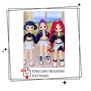 Puede incluir: Tres muñecas tejidas a mano con cabello de hilo en azul, morado y rojo. Cada muñeca viste una chaqueta corta azul marino con ribetes dorados, un top blanco y una falda blanca con detalles dorados. Llevan botas blancas con cordones. Texto: PDF ENGLISH/SPANISH PATTERN.