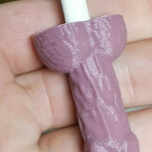 May include: A 3D printed, light pink, pen holder shaped like a human body part. The pen holder is designed to hold a standard-sized pen or pencil.