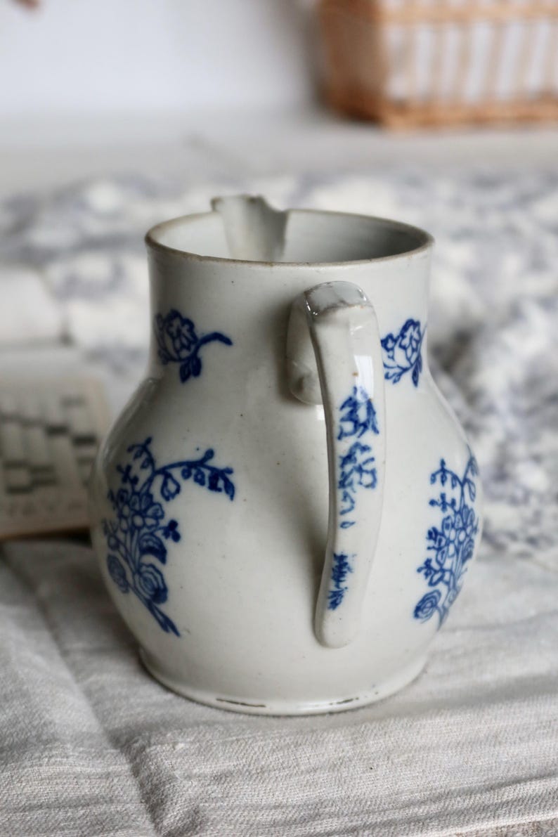 Puede incluir: Jarra de cer&aacute;mica blanca con motivos florales azules. La jarra tiene un asa curva y un pico para verter. El dise&ntilde;o floral azul se repite alrededor del cuerpo y en el asa. Una pieza cl&aacute;sica para servir bebidas.