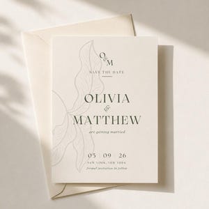 May include: A cream-colored save the date card with a matching envelope. The card features a delicate line-art leaf design, the text O&M, SAVE THE DATE, OLIVIA & MATTHEW, are getting married, 05 09 26, NEW YORK, NEW YORK, and formal invitation to follow.