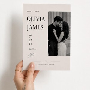May include: A rectangular save the date card with a light beige background featuring a black and white photograph of a couple. The text reads Olivia and James, 09.26.27, Seattle, Washington, and formal invitation to follow, with a small leaf illustration.