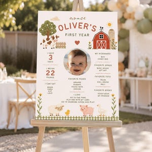 Puede incluir: Un cartel de hitos blanco titulado Oliver's First Year con una foto central de un bebé, ilustraciones de animales de granja como vaca, oveja, cerdo y pato, un granero rojo y texto que detalla 3 dientes, 22 libras, apodos, comidas favoritas, canciones, juguetes, libros y actividades.