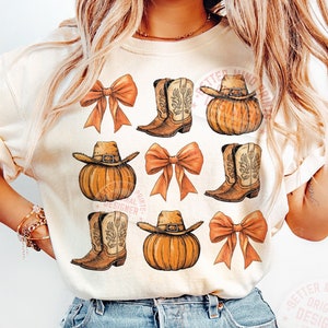 May include: A white t-shirt with a pattern of brown cowboy boots, orange pumpkins, and pink bows. The shirt has the text "Better Mind Prints. Original Designer" on the bottom right corner.