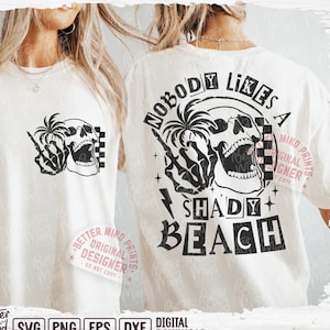 May include: A white t-shirt with a black and white graphic design of a skull with a palm tree and the text "Nobody Likes a Shady Beach".