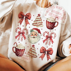 May include: Cream-colored sweatshirt featuring a festive Christmas design. The design includes red bows, candy canes, Santa Claus, Christmas trees, and mugs of hot cocoa. The words "Better Mind Prints" and "Digital Download" are visible.
