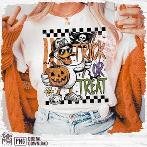 May include: White t-shirt with a Halloween-themed graphic. The design features a cartoon duck wearing sunglasses and a hat, holding a carved pumpkin and a flag that says "Trick or Treat". The duck is wearing Crocs. The shirt has the words "Spooky Dude".