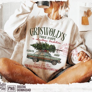 May include: Cream-colored sweatshirt with a graphic of a vintage green car carrying a Christmas tree. The text reads "Griswold's Tree Farm, a Christmas tradition, since 1989." The design includes the phrase "home for the fun old fashioned family Christmas."