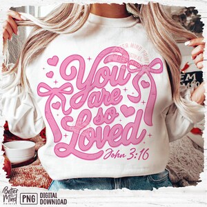 May include: White sweatshirt with a pink graphic design that says "You are so loved" with hearts and stars. The text "John 3:16" is below the graphic.