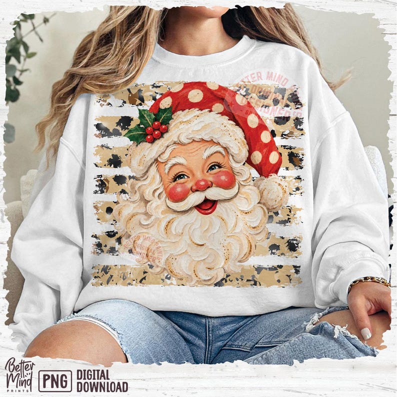 May include: A white long-sleeve sweatshirt featuring a central graphic of a smiling Santa Claus wearing a red hat with white polka dots. The background of the graphic consists of horizontal beige stripes with a black leopard print pattern.