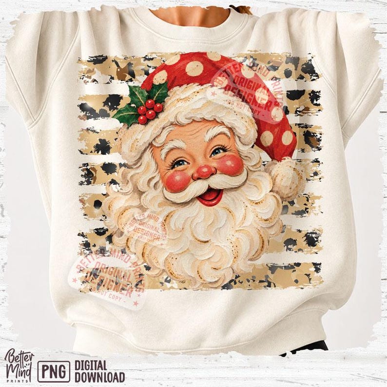 May include: A cream-colored sweatshirt featuring a graphic of Santa Claus with a white beard, red hat with white polka dots, and green holly leaves. The design is set against a background of horizontal tan and black leopard print stripes.