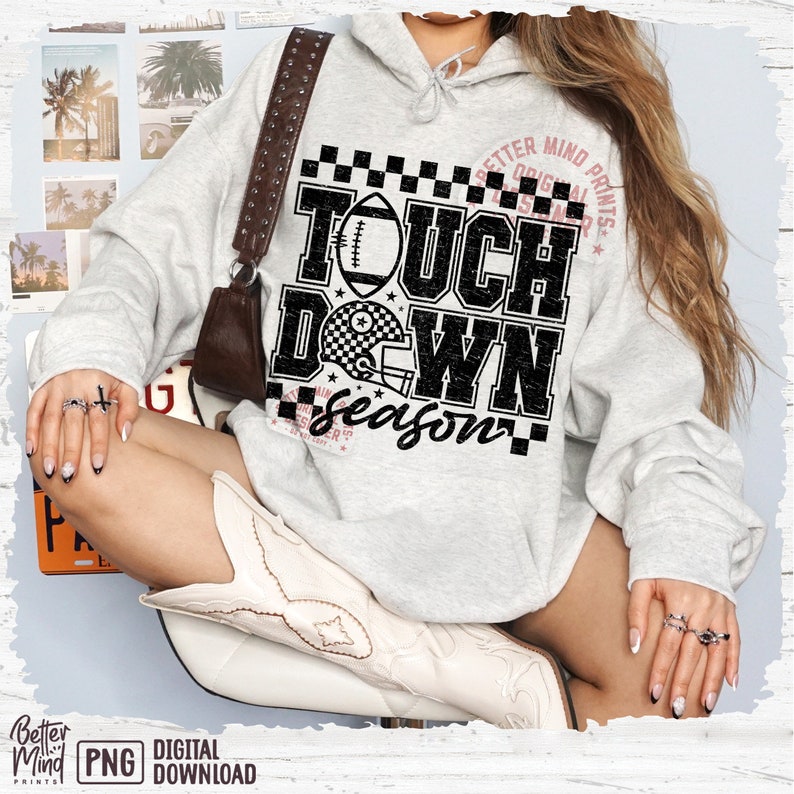 May include: A gray hoodie with a black and white graphic print that says "Touch Down Season" with a football and helmet design. The graphic has a distressed look and is surrounded by a checkered pattern.