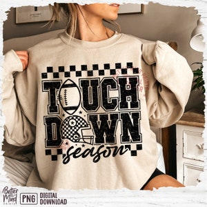 May include: A beige sweatshirt with a black graphic print that says "Touchdown Season" with a football and a helmet. The graphic has a distressed look.
