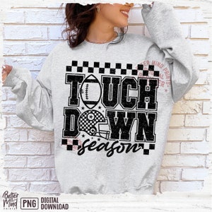 May include: A gray sweatshirt with a black and white graphic design that says "Touch Down Season". The graphic includes a football, a helmet, and a checkered pattern.