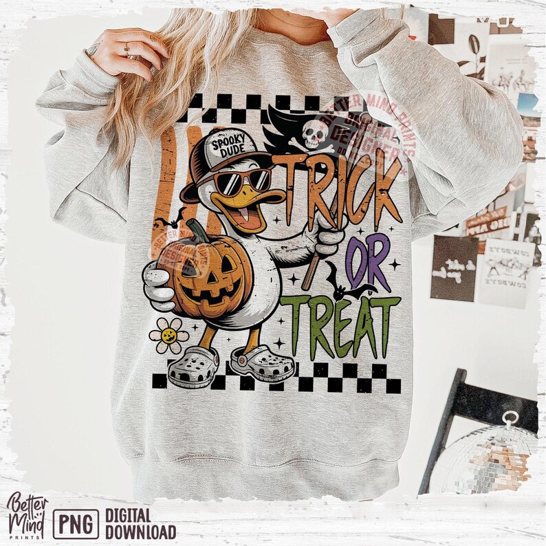 May include: A gray sweatshirt with a Halloween-themed graphic. The graphic features a cartoon duck wearing sunglasses and a hat, holding a pumpkin and a trick-or-treat sign. The words "Trick or Treat" are prominently displayed.