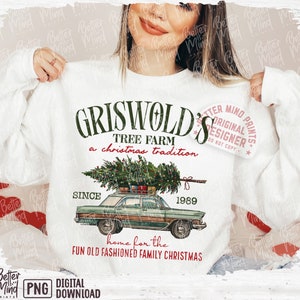 May include: White sweatshirt with a graphic featuring the text "GRISWOLD'S TREE FARM a christmas tradition" and a vintage car carrying a Christmas tree. The design includes the year "1989" and the phrase "home for the FUN OLD FASHIONED FAMILY CHRISTMAS."
