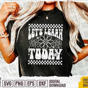 May include: A black t-shirt with a white graphic design that says "Let's Learn Today" in a retro font. The graphic also includes a checkered border and a flower with a smiley face.