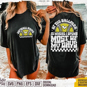 May include: Black t-shirt with a white graphic design featuring a softball with a heart and the text "Softball Mama". The back of the shirt has a white graphic design with a softball and the text "At the Ballpark is where I spend most of my days".