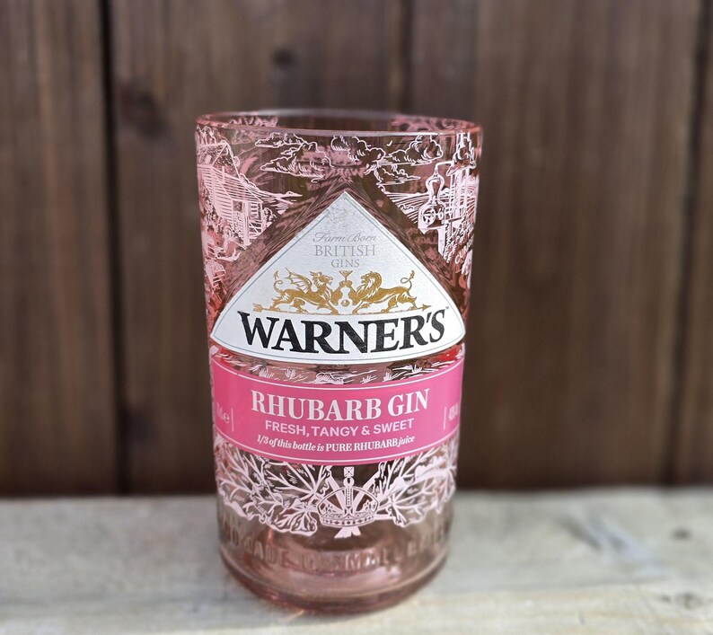 May include: A pink glass bottle of Warner's Rhubarb Gin. The label says "Farm Grown British Gins" and "Rhubarb Gin Fresh, Tangy & Sweet". 1/3 of this bottle is pure rhubarb juice.