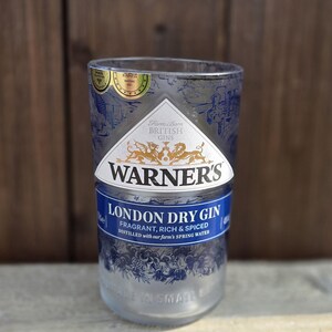 May include: A clear glass bottle with a blue and gold label that reads "Warner's London Dry Gin". The label also says "Fragrant, Rich & Spiced" and "Distilled with our farm's spring water".