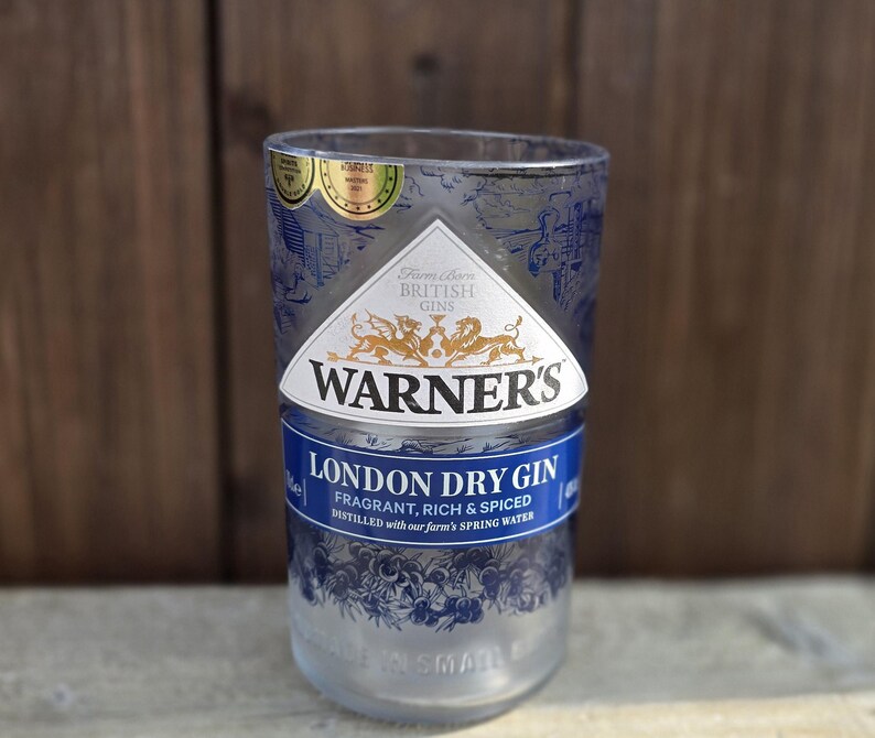 May include: A clear glass bottle with a blue and gold label that reads "Warner's London Dry Gin". The label also says "Fragrant, Rich & Spiced" and "Distilled with our farm's spring water".
