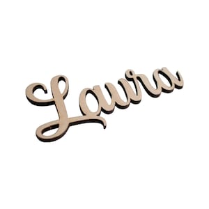 Könnte beinhalten: Ein Holzschild mit dem Namen "Laura" in Kursivschrift.