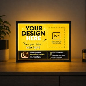 Könnte beinhalten: Ein schwarzer Leuchtkasten mit einem hellgelb beleuchteten Zentrum. Der Text "YOUR DESIGN HERE" wird angezeigt, zusammen mit "Turn your ideas into light". Es enthält ein Kamera-Symbol und den Satz "Laden Sie Ihr eigenes Foto, Logo oder Ihre Nachricht hoch und erstellen Sie Ihre individuelle Leuchtbox!"