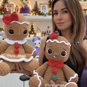 May include: Two brown crocheted gingerbread plush dolls with large black eyes, white icing-style trim, and red accents. One doll features a red bow on its head, while the other has a red bowtie. Both dolls display the text @kro_shaa.
