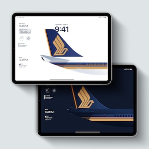 Op de afbeelding: Twee digitale tablets met een gestileerd vliegtuigstaartontwerp in marineblauw, goud en wit. De bovenste tablet heeft een witte achtergrond, de onderste een donkerblauwe achtergrond. Beide tonen de tijd en datum.