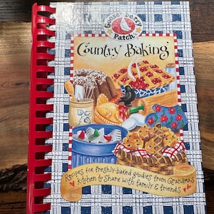 May include: A spiral-bound cookbook titled "Country Baking" with a red spine. The cover features illustrations of baked goods and the text "Recipes for freshly-baked goodies from Grandma's Kitchen to Share with family & friends."