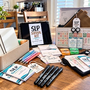May include: An SLP survival kit containing a tablet displaying the text SLP SURVIVAL KIT, a beige storage bin with white dry-erase boards, colorful pens, black markers, a brown pouch, and various communication cards with alphabet and quick scan charts.