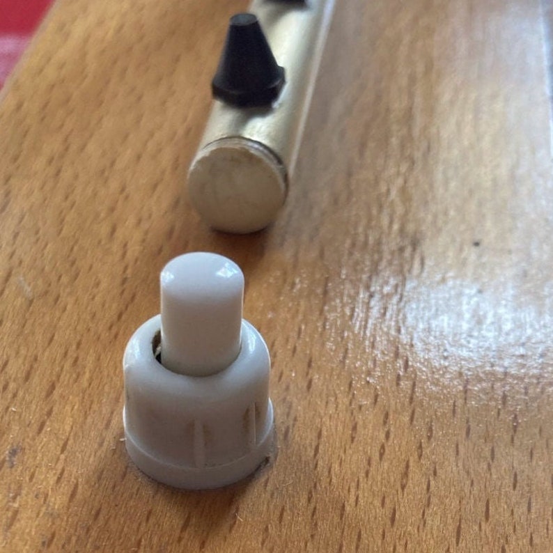 May include: A white plastic toggle switch with a round knob. The switch is mounted on a wooden surface.