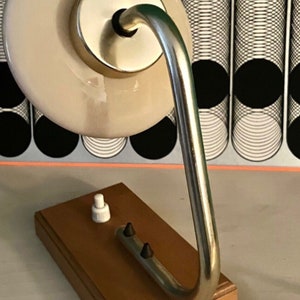 May include: A vintage desk lamp with a white ceramic shade and a chrome arm. The lamp has a wooden base with a cord and switch.