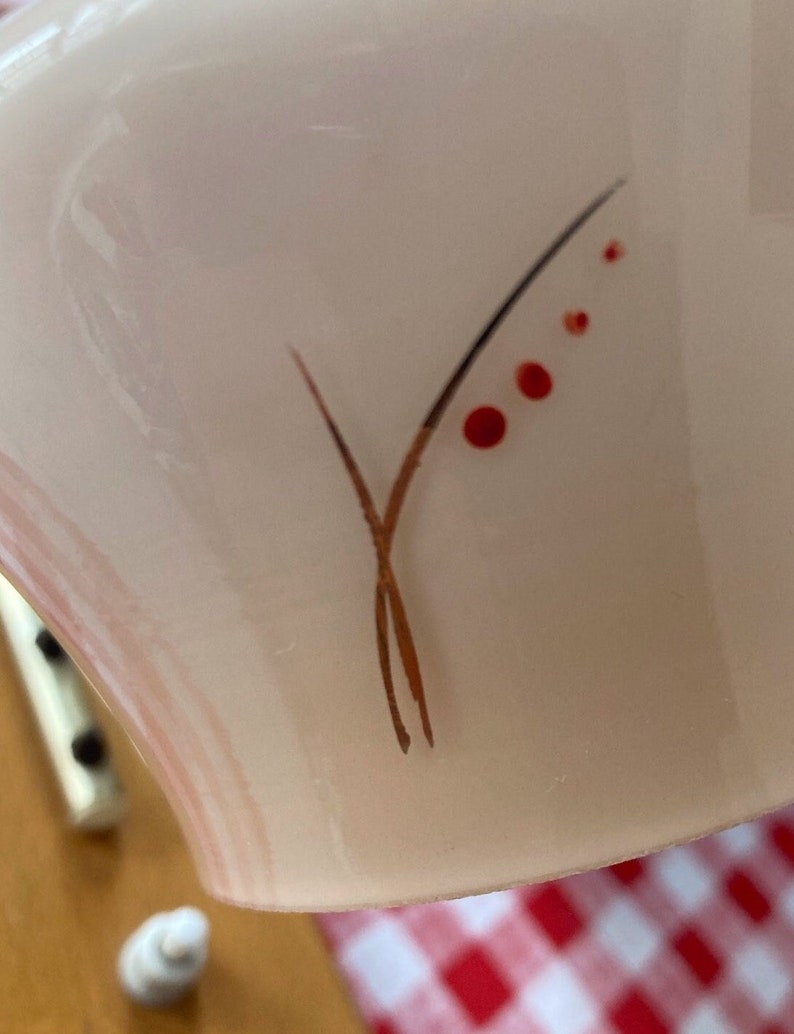 May include: A white ceramic bowl with a delicate brown and red floral design. The design features a stylized branch with red berries.