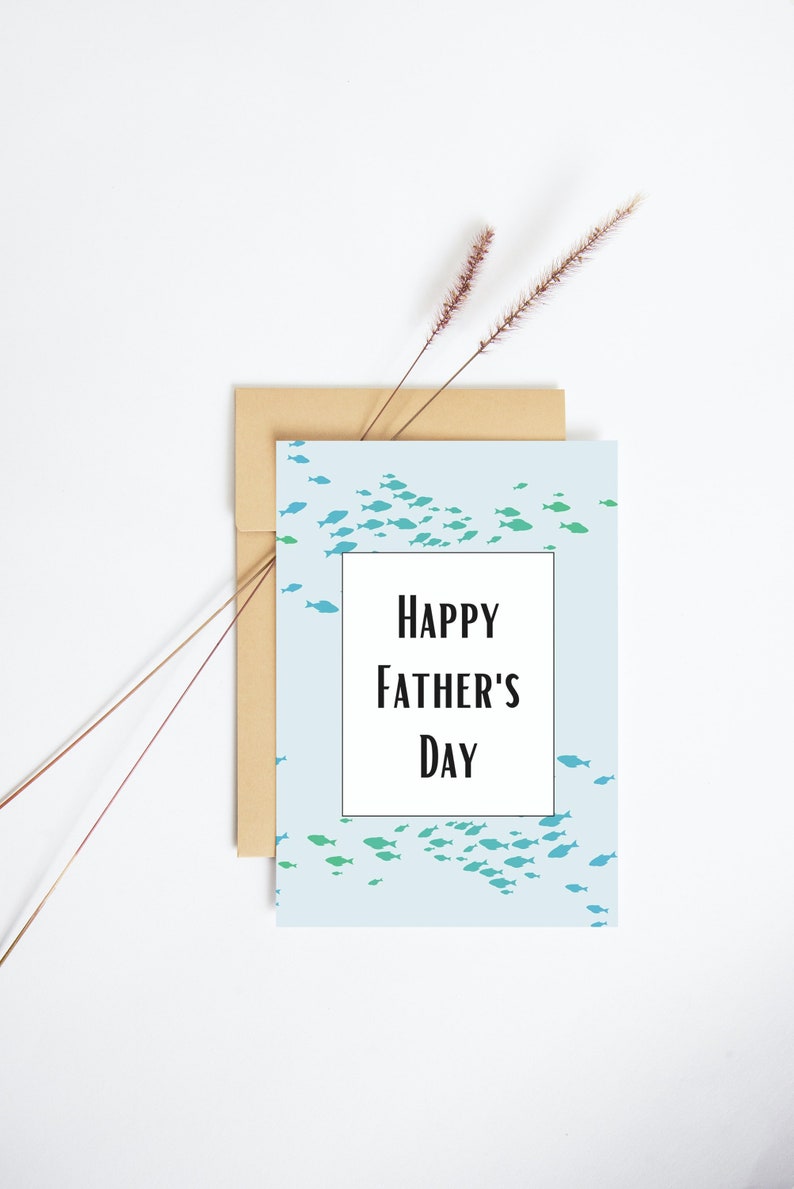 May include: A light blue card with a school of blue and green fish printed on it. The card has a white rectangle in the center with the text "HAPPY FATHER'S DAY" in black.
