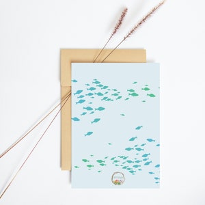 May include: A light blue card with a school of teal and blue fish swimming in a pattern. The card has a small floral logo in the bottom right corner that says "Simply Made Pretty".